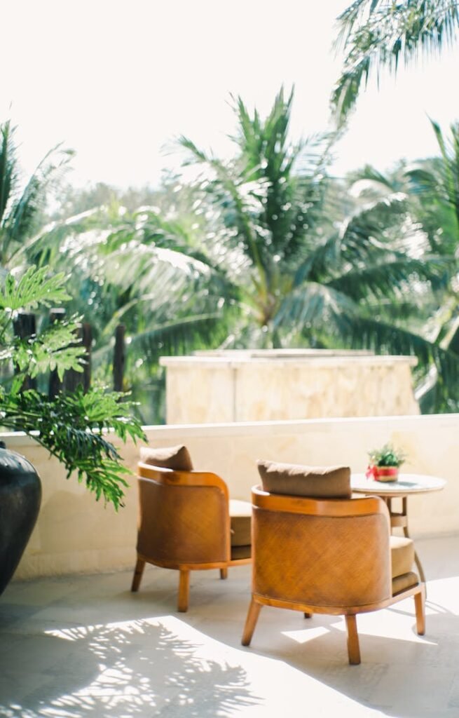 Luxurious chairs on a resort patio with lush palm trees, perfect for a summer getaway.